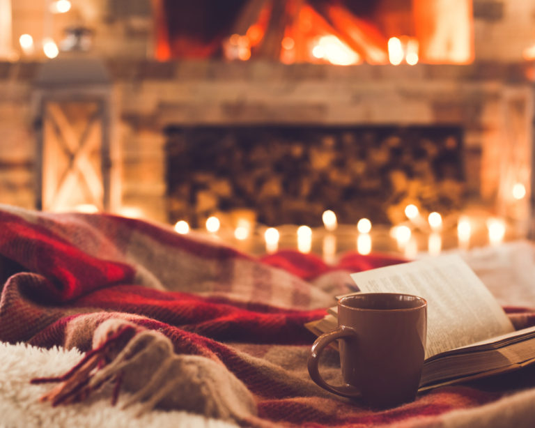 One cup and a book near the fireplace winter concept